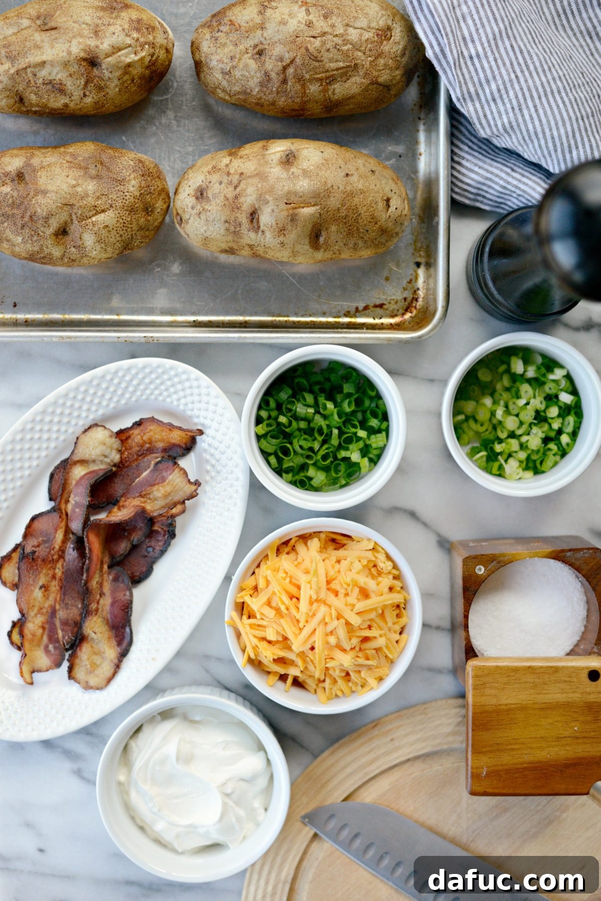Decadent Double-Baked Potato Delight 4 Ingredients for Loaded Twice Baked Potatoes laid out: potatoes, bacon, cheese, sour cream, green onions, olive oil