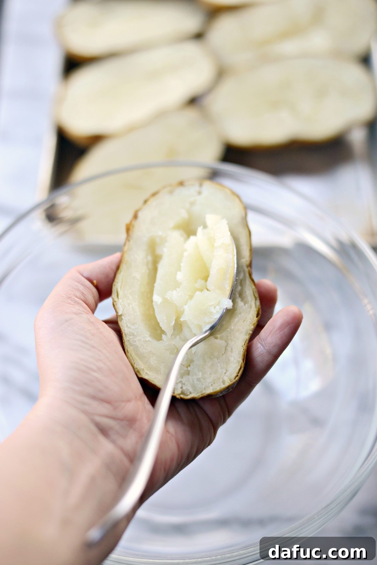 Decadent Double-Baked Potato Delight 6 Scooping the fluffy potato flesh out of the baked skin into a mixing bowl