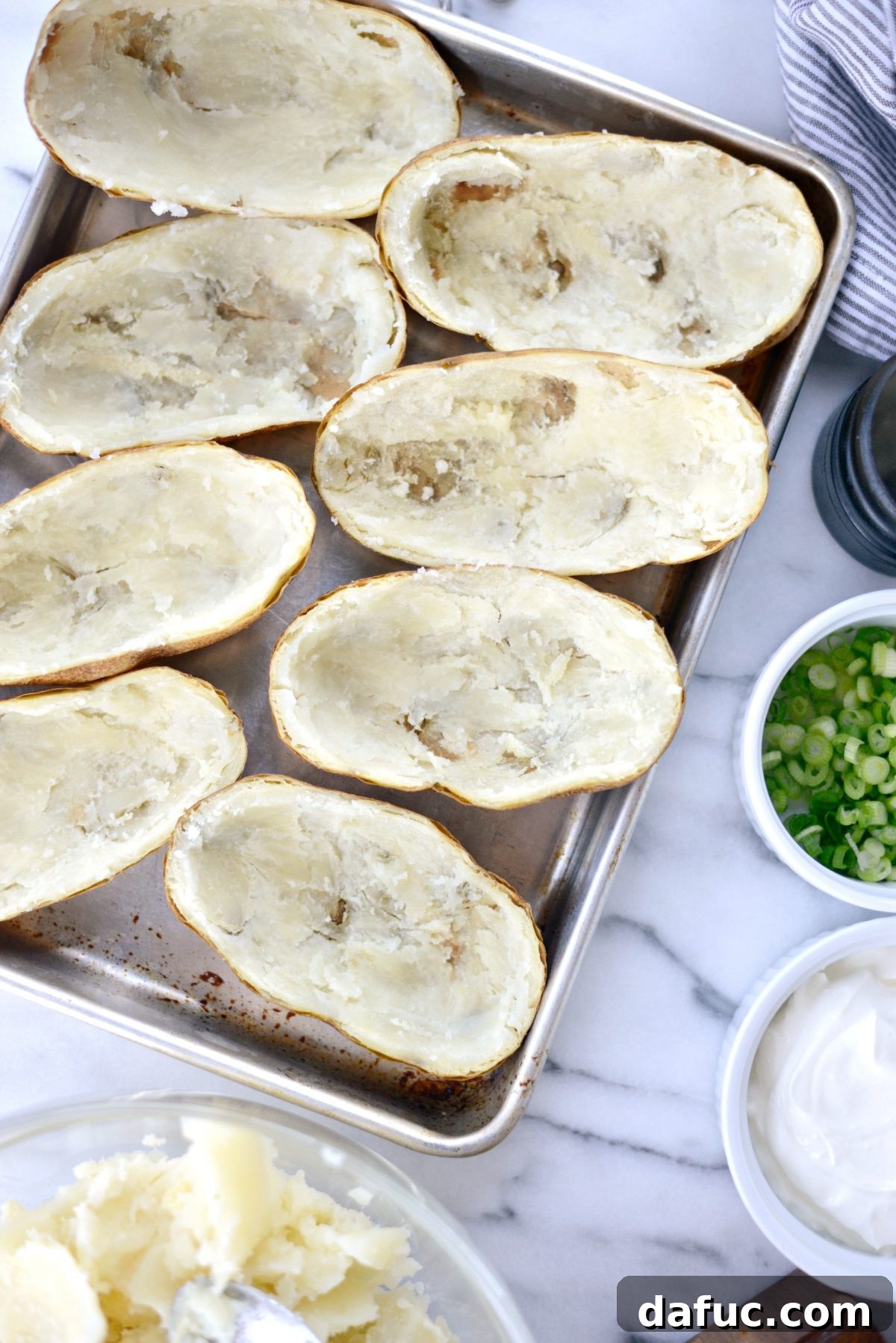 Decadent Double-Baked Potato Delight 7 Hollowed potato skins lined up on a baking sheet