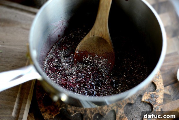 Two tablespoons of chia seeds being sprinkled into the cherry jam.