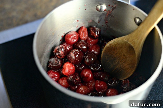 Cherries simmering gently in a heavy-bottomed saucepan on the stovetop.
