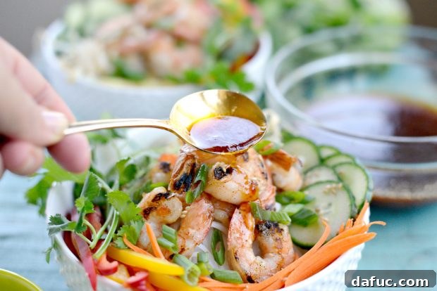 Vibrant Grilled Shrimp Spring Roll Noodle Bowls 12 Savory dressing being drizzled over the colorful grilled shrimp spring roll noodle bowl.