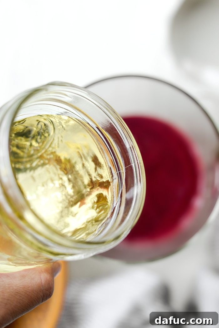 Adding white wine simple syrup to the blueberry lemon mixture in a pitcher