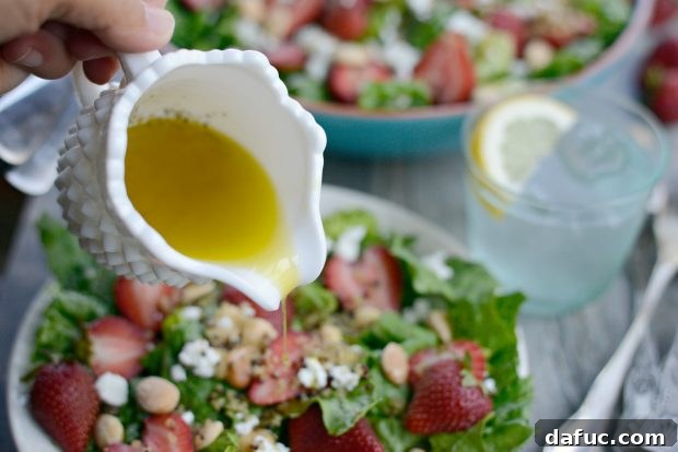 Sweet Strawberry and Creamy Goat Cheese Salad with Crispy Quinoa 17 Dressing being poured over the salad