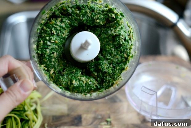 Mixing pasta with spinach almond pesto