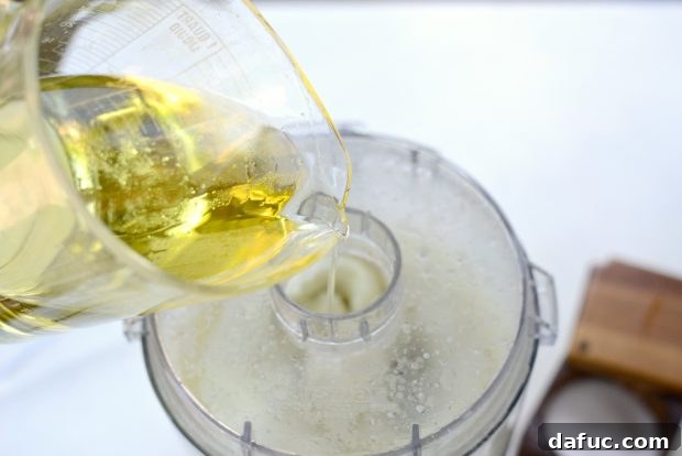 Creamy Lebanese Toum 10 Slowly pouring oil into the running food processor.