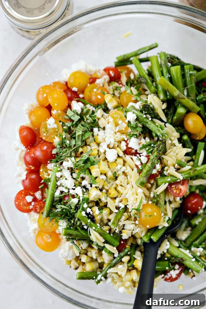 Vibrant Grilled Corn Orzo Salad 14 The salad ingredients are being tossed together in the large mixing bowl to combine all the fresh flavors.