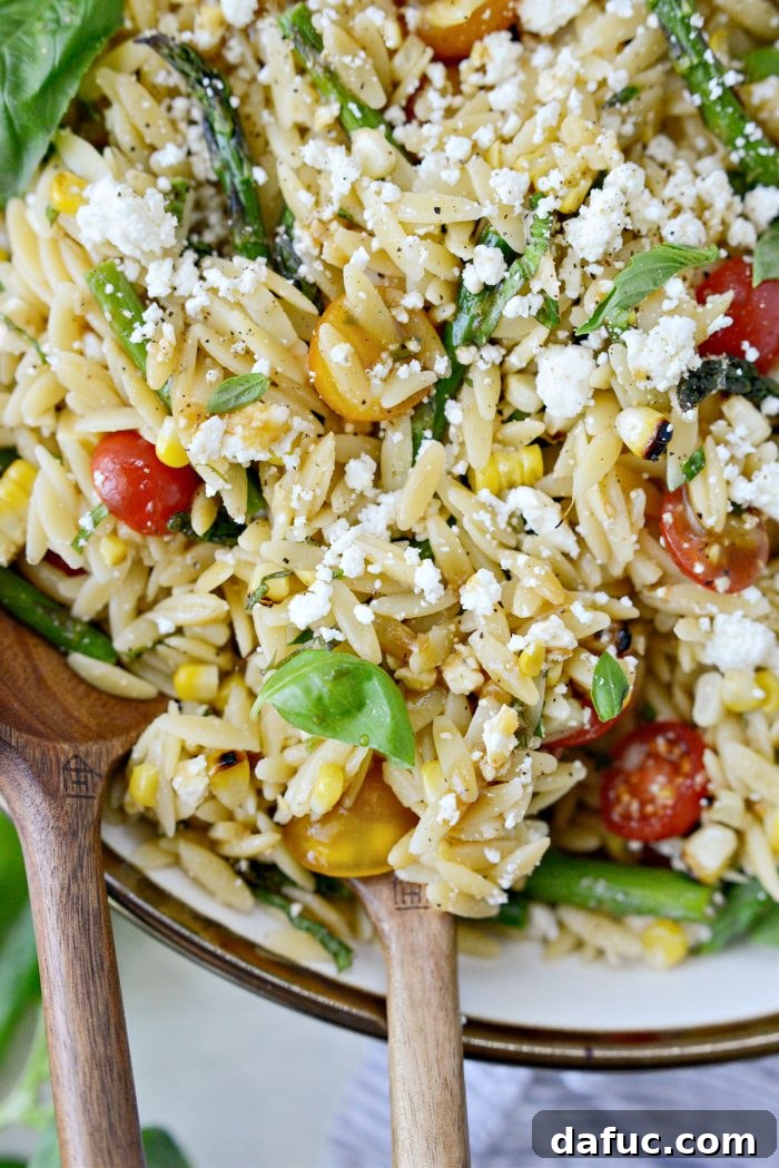 Vibrant Grilled Corn Orzo Salad 19 A wider shot of the Asparagus Tomato and Grilled Corn Orzo Pasta Salad in a serving bowl, set in a summer outdoor dining scene.