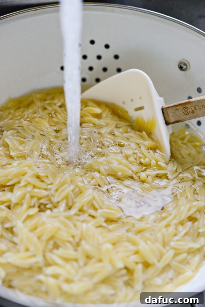 Vibrant Grilled Corn Orzo Salad 8 Cooked orzo pasta being drained in a colander under cool running water.