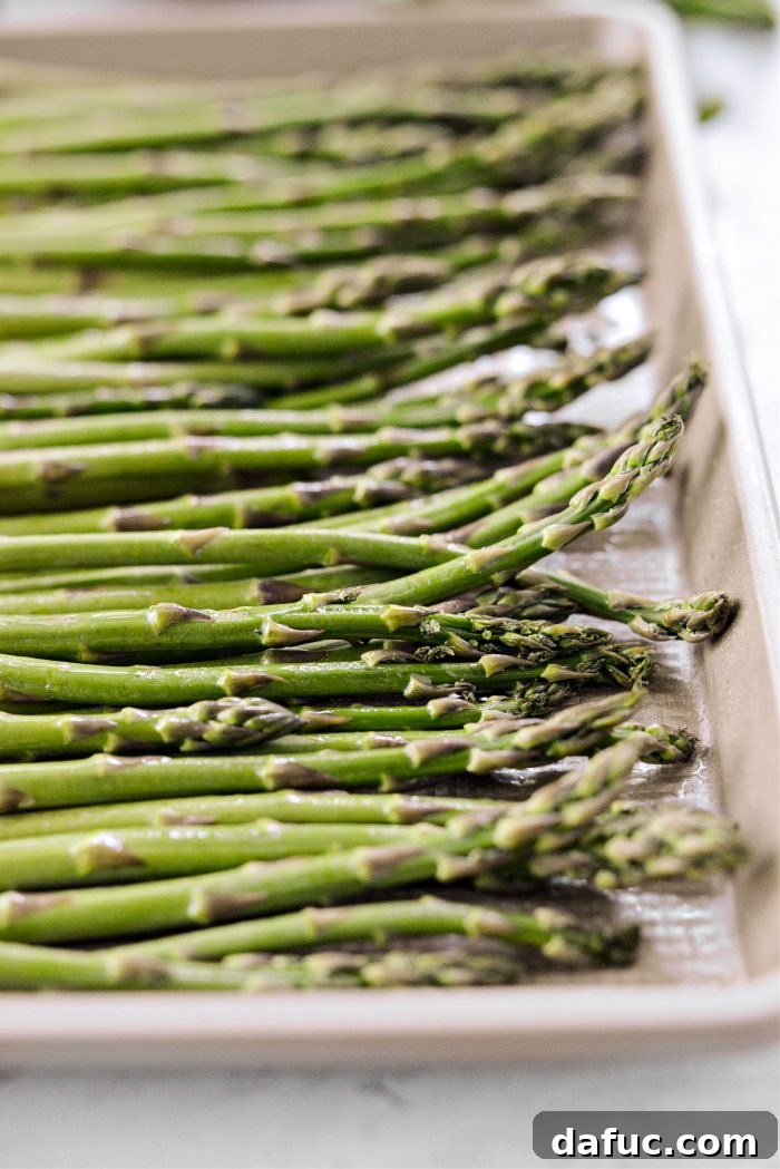 Vibrant Grilled Corn Orzo Salad 9 Fresh asparagus stalks laid out on a baking sheet, lightly coated with olive oil spray, ready for roasting.