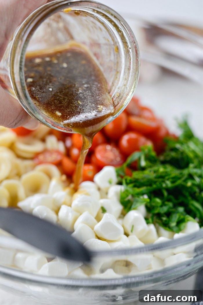 Garden Fresh Caprese Pasta 11 Pouring dressing over the pasta salad ingredients