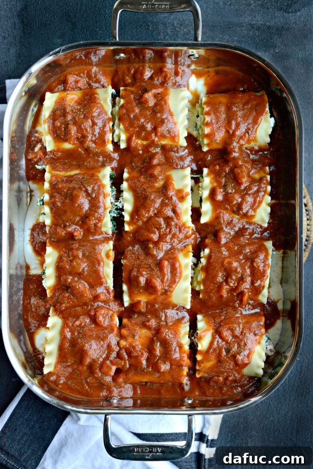 Marinara sauce generously spooned over the assembled lasagna roll-ups