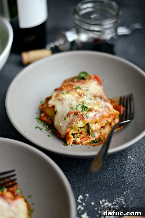 A serving of lasagna roll-ups alongside a fresh green salad and a glass of red wine, completing a perfect meal