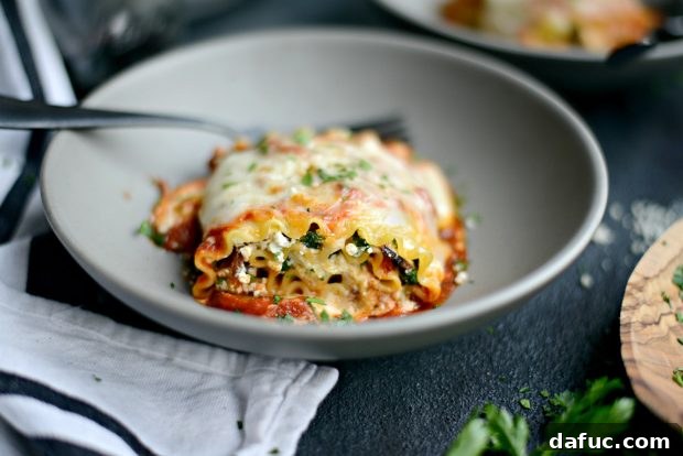 Two lasagna roll-ups served with a side of green salad and a glass of red wine