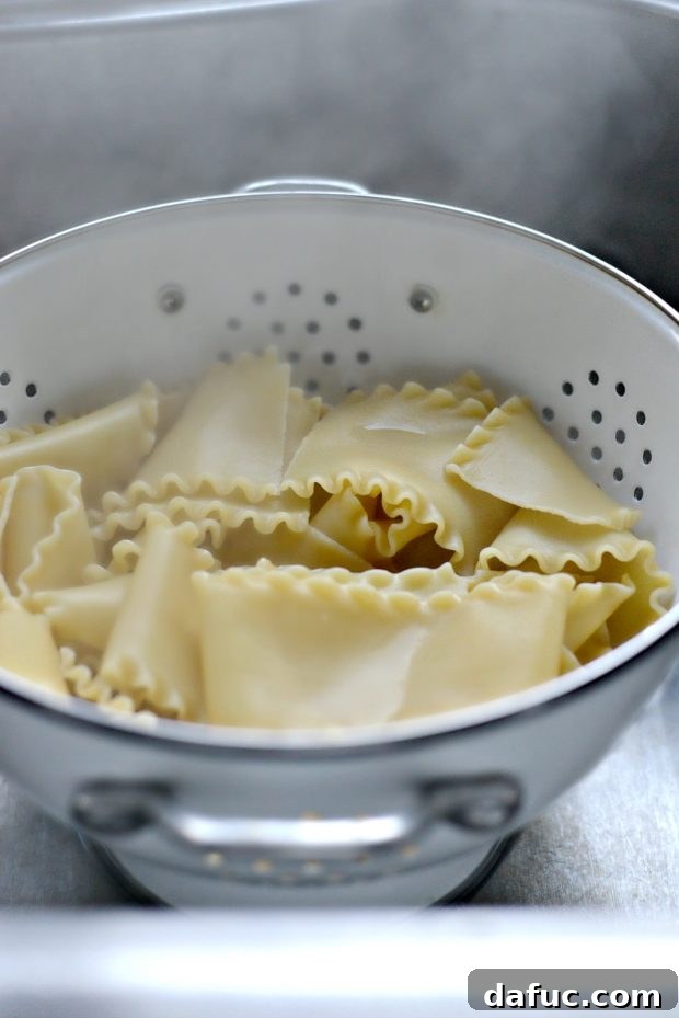 Partially cooked lasagna noodles laid out on parchment paper to cool
