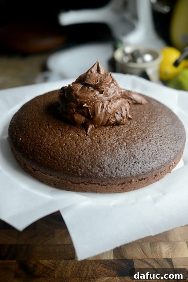 Beginning the frosting process on a chocolate cake, spreading the first layer of whipped chocolate frosting