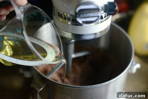 Water and grapeseed oil being poured into the homemade cake mix in a stand mixer
