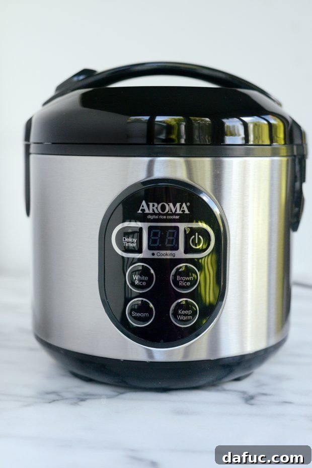 Effortless Rice Cooker Coconut Rice 7 A closed rice cooker with the 'White Rice' button illuminated, indicating it's ready to cook.