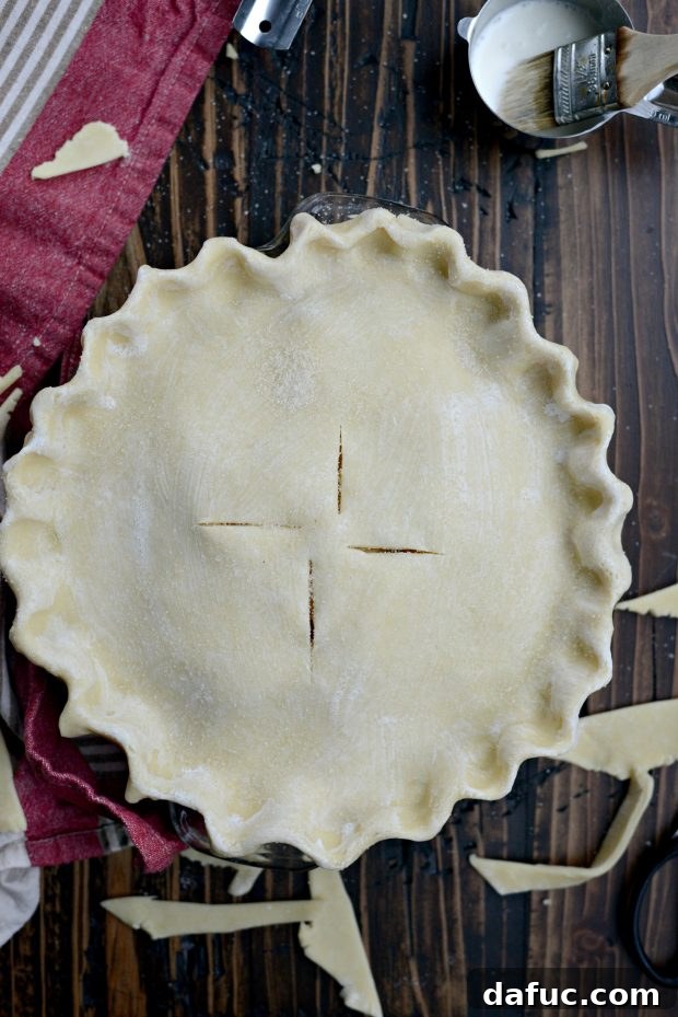 Top with second pie crust, fold and pinch edges and cut air vents. brush with cream and sprinkle with sugar.