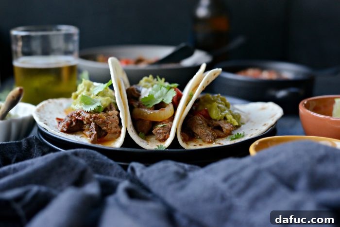 Delicious Slow Cooker Steak Fajitas served in tortillas with toppings