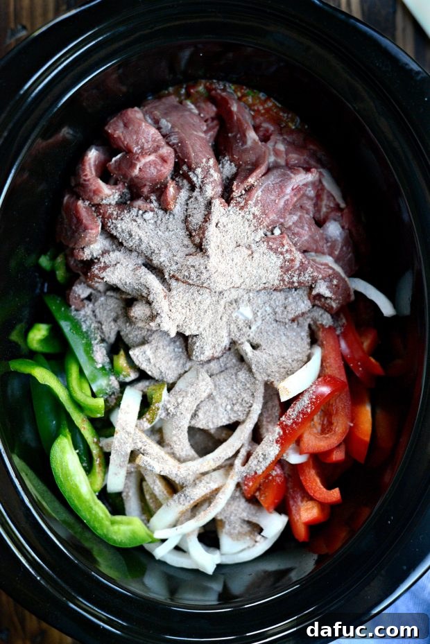 Sprinkling fajita seasoning over the beef and vegetables in the slow cooker