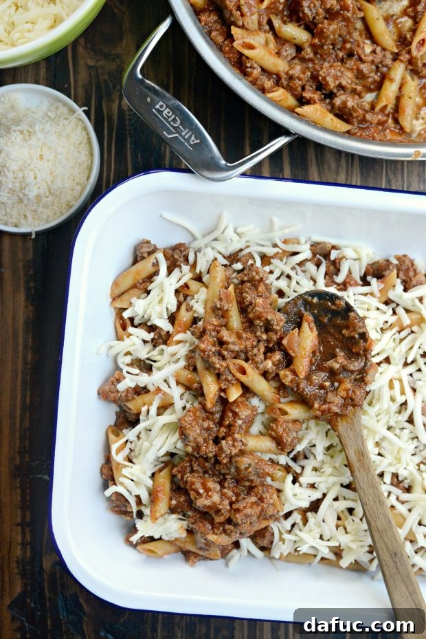 Layering meat and pasta mixture with mozzarella cheese in a baking dish