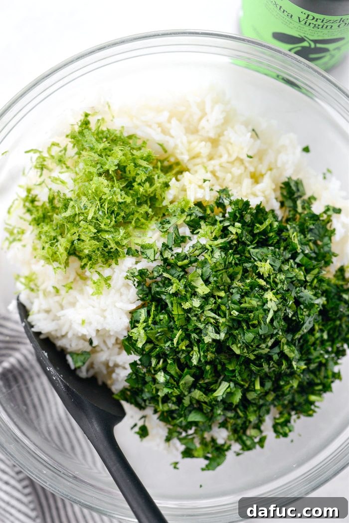 Cooked rice transferred to a mixing bowl with chopped cilantro, lime zest, and olive oil