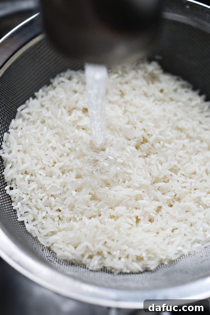 Rinsing long grain white rice in a mesh strainer under running water