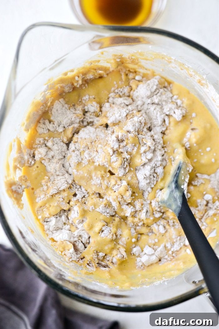 Spiced Brown Butter Pumpkin Pancakes 10 A spatula gently folding the wet and dry ingredients together, ensuring minimal mixing for tender pancakes.