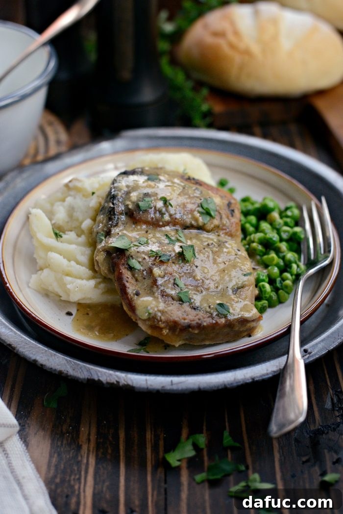 Plated slow cooker pork chops with herb gravy and a side of green peas