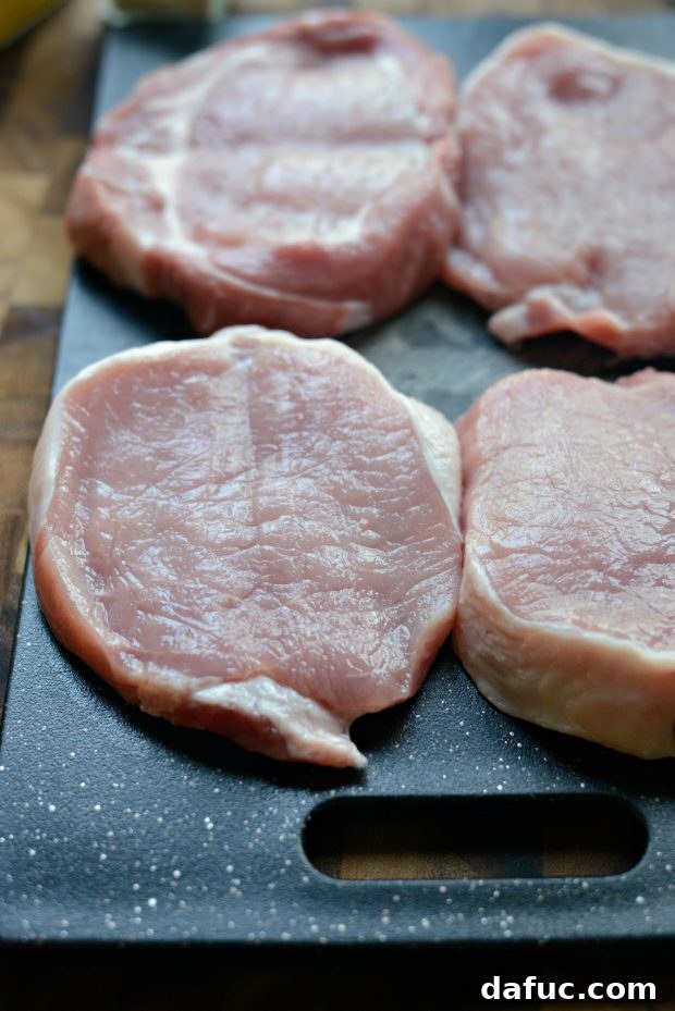 Raw pork chops on a cutting board, ready for seasoning