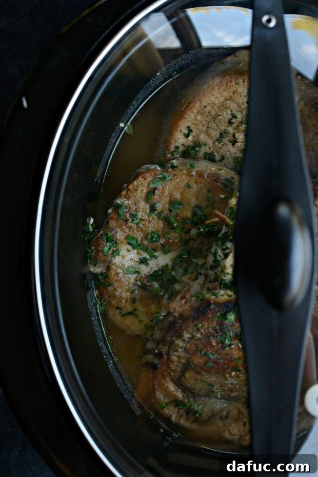 Slow cooker covered and cooking pork chops with herb gravy