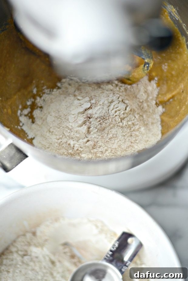 Gradually adding dry ingredients to the wet ingredients for pumpkin coffee cake batter