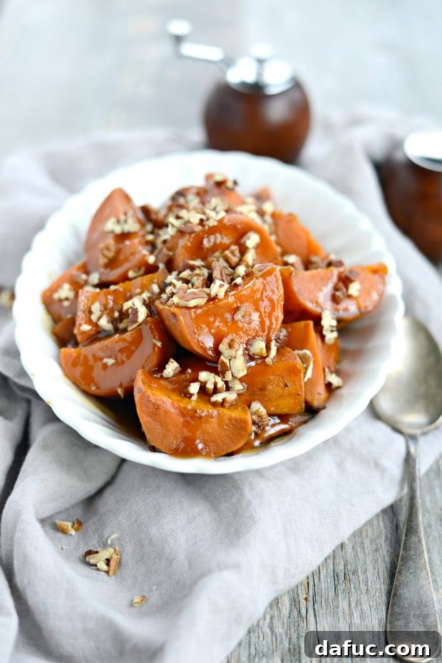 Close-up of slow cooker candied sweet potatoes in a bowl, topped with chopped pecans.