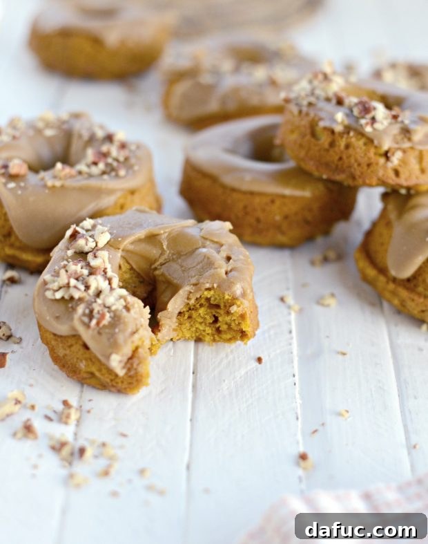 A close-up shot of a single glazed baked pumpkin doughnut, showing its tender crumb