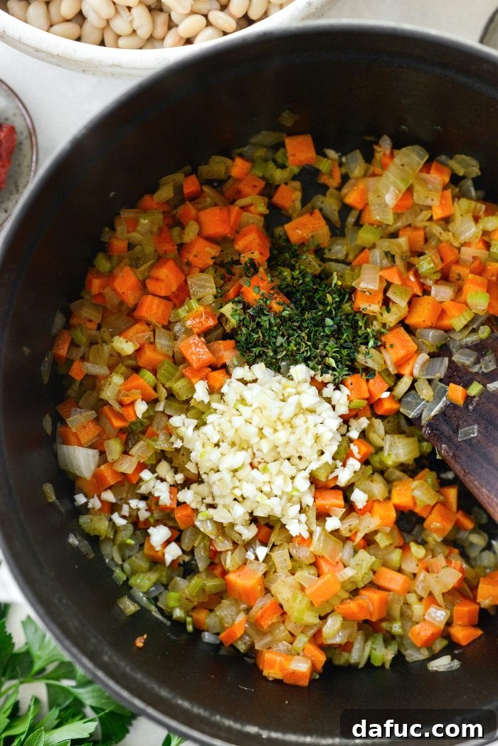 Smoky Bean and Bacon Delight 11 Adding minced garlic and fresh thyme to the softened vegetables, enhancing the aromatic foundation of the soup.