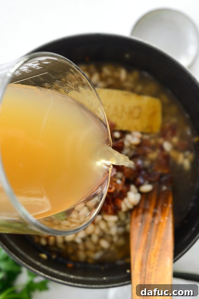 Smoky Bean and Bacon Delight 15 Pouring low-sodium chicken broth into the soup pot, creating the liquid base for the comforting dish.