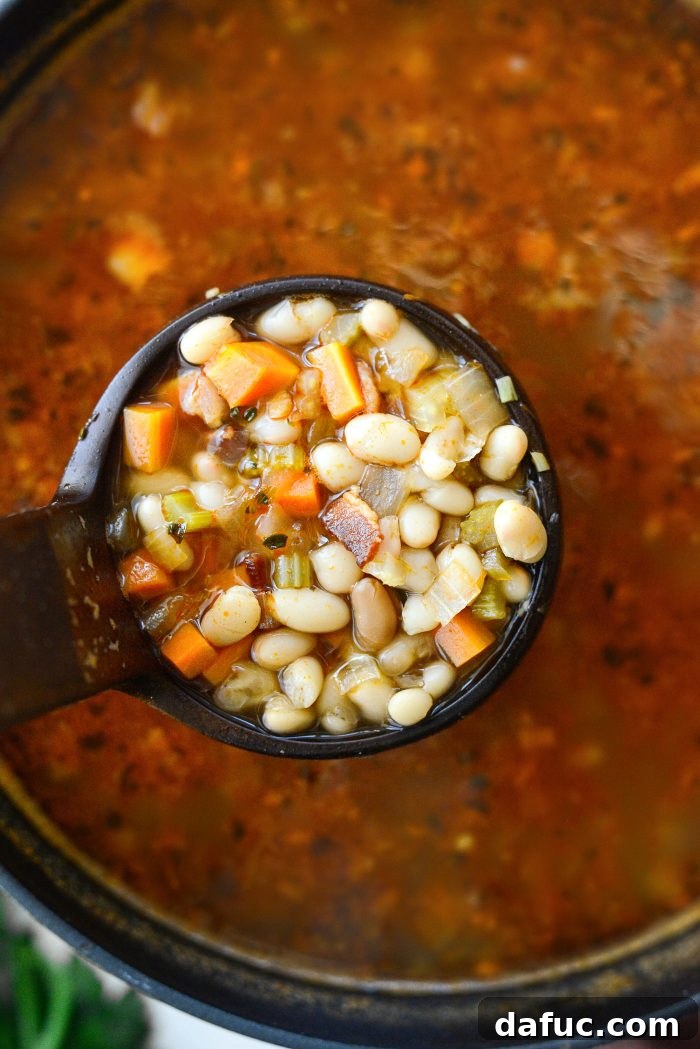 Smoky Bean and Bacon Delight 20 A ladle serving hot homemade Bean and Bacon Soup into a clean white bowl.