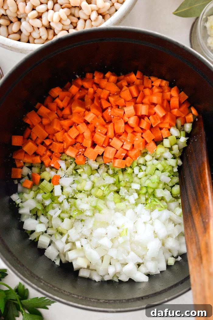 Smoky Bean and Bacon Delight 9 Adding diced onion, celery, and carrot with a pinch of kosher salt to the reserved bacon fat in a Dutch oven, starting the soup base.