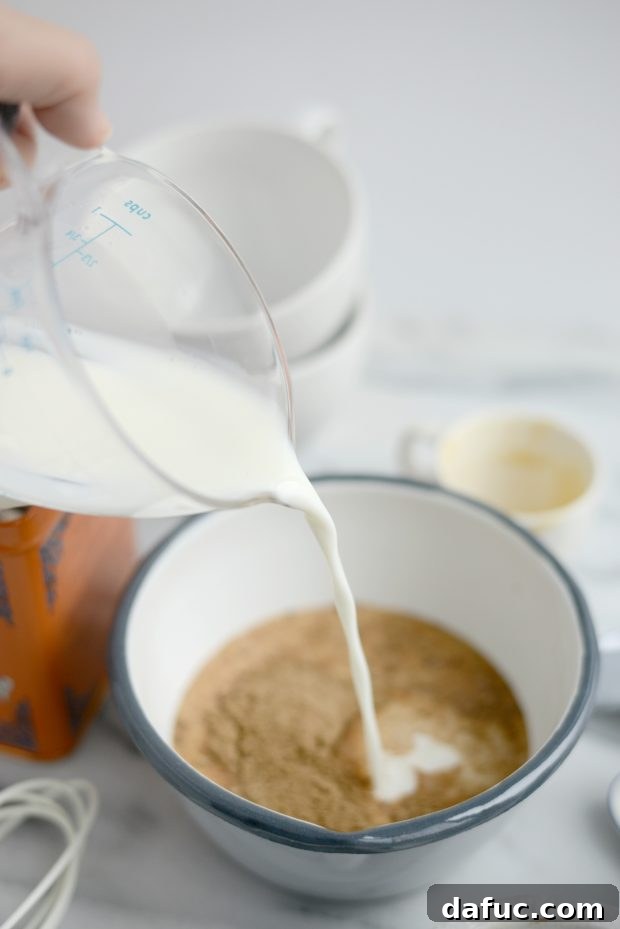 Spiced Comfort Masala Chai 9 Spiced milk being poured through a fine mesh strainer into a mug of black tea