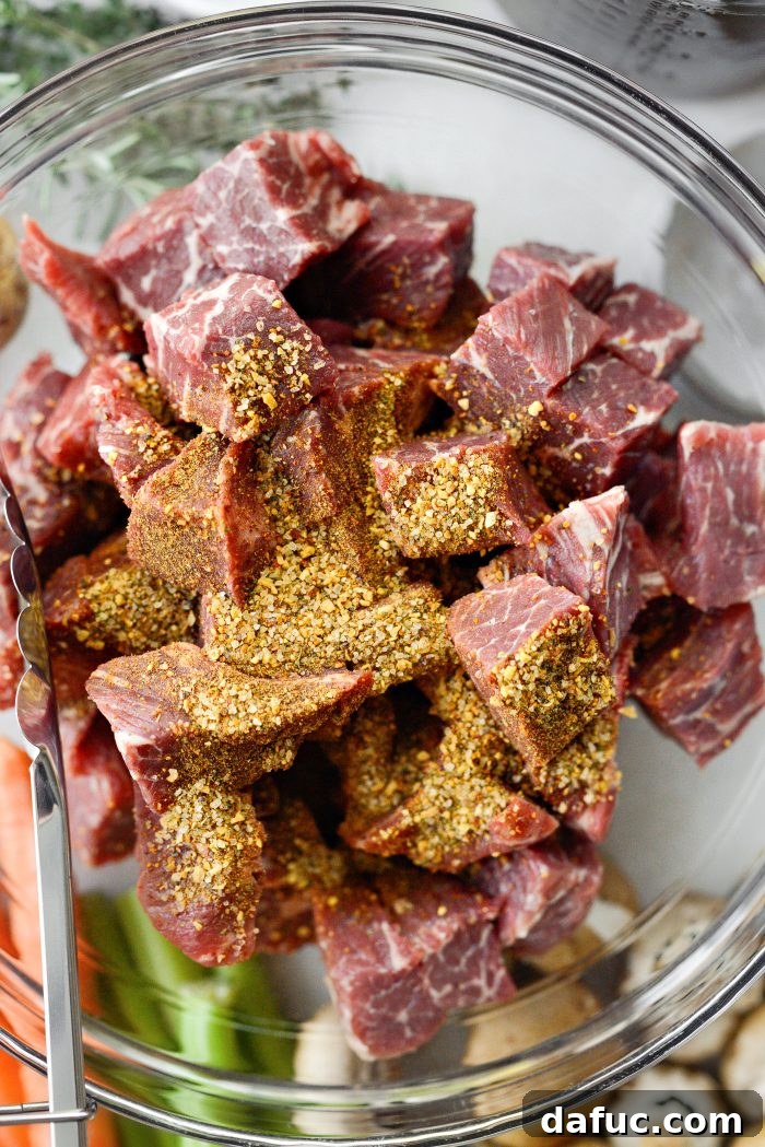 Seasoning cubed beef with steak seasoning in a bowl