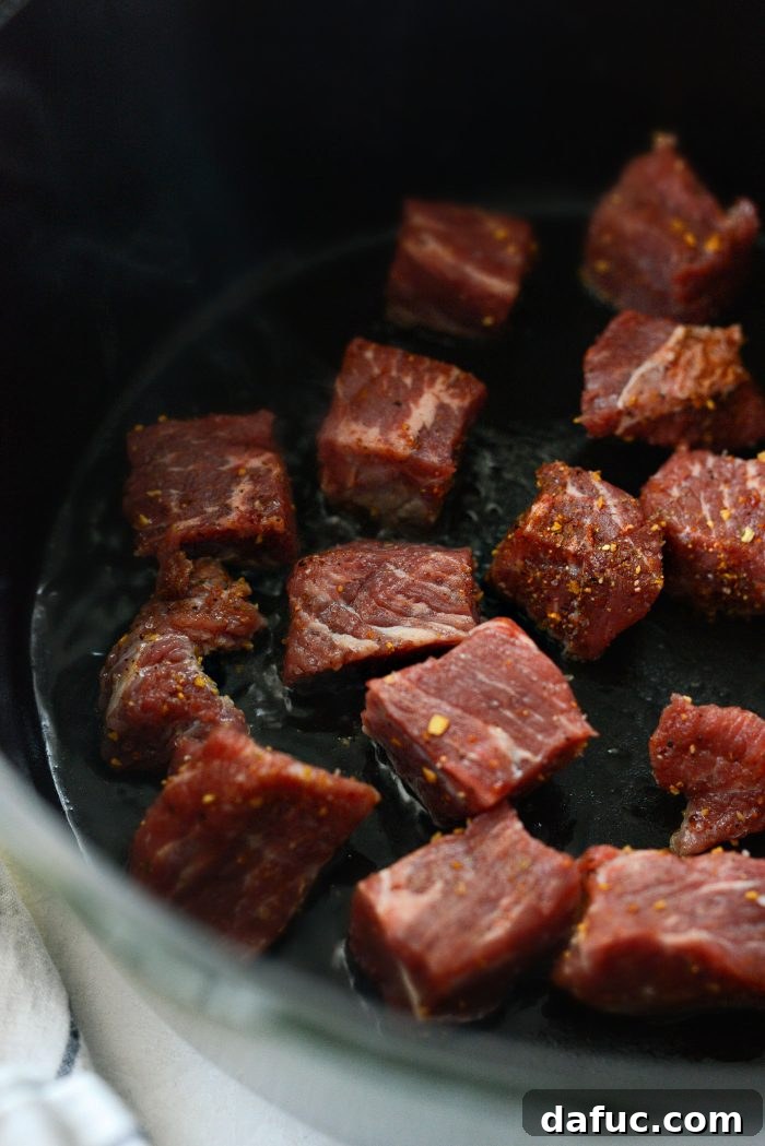 Searing beef in batches in a Dutch oven until deeply golden