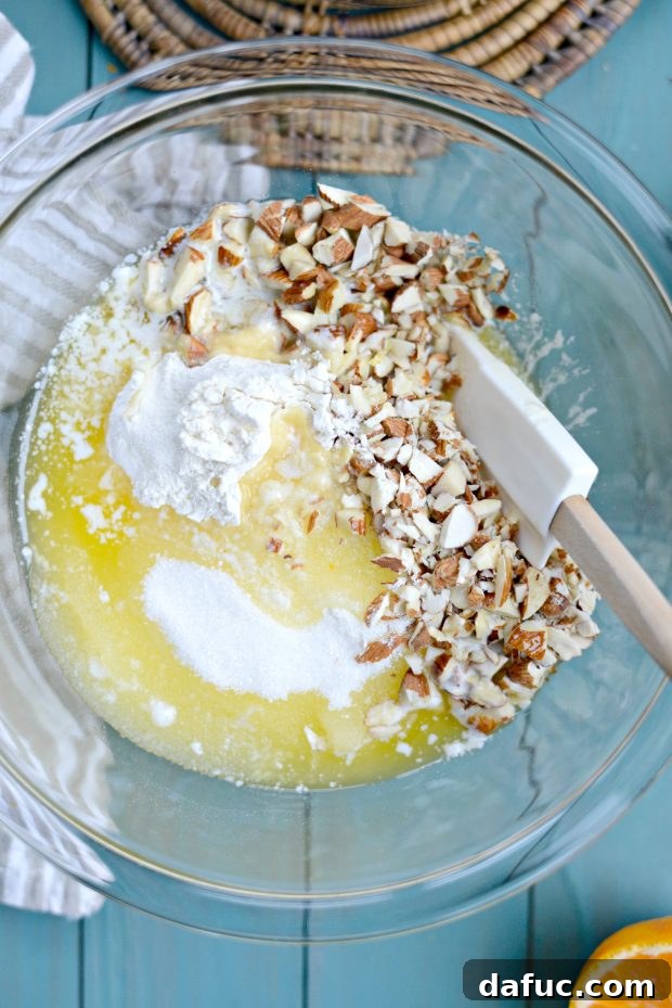 Mixing melted butter into dry ingredients and chopped nuts to create the crumble topping