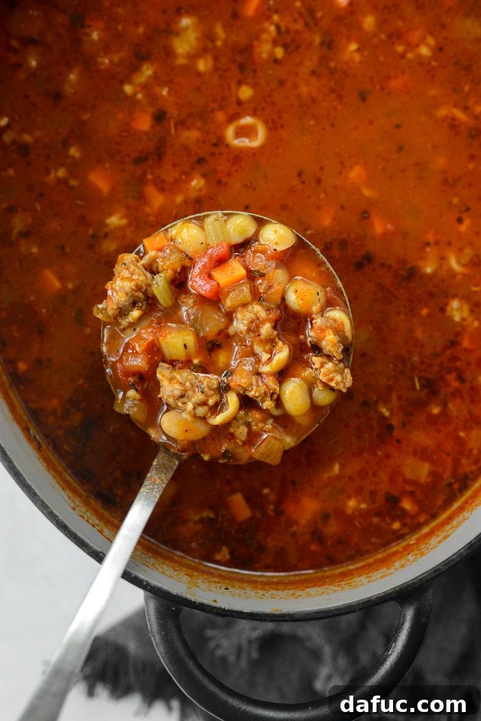 Ladling a serving of warm Italian Sausage White Bean Soup into a bowl