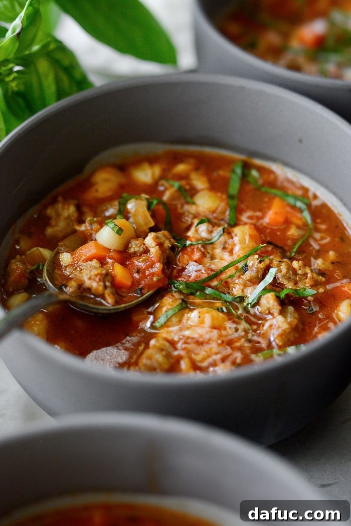 A warm bowl of Italian Sausage White Bean Soup with fresh bread beside it