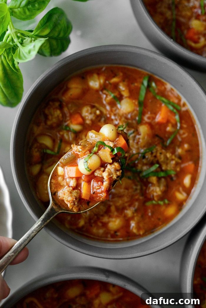 Last appetizing image of Italian Sausage White Bean Soup in a bowl on a wooden surface