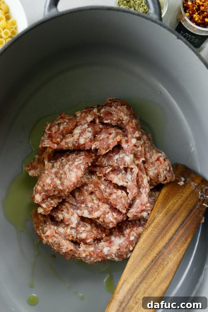 Adding olive oil and Italian sausage to a Dutch oven for browning