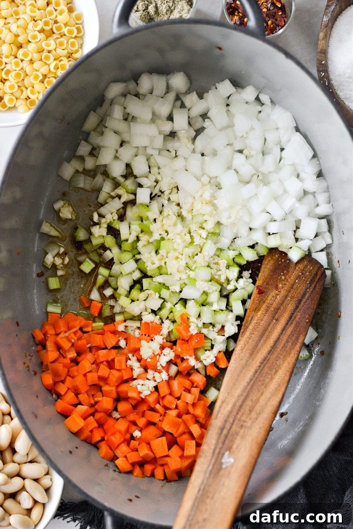 Sautéing onions, celery, and carrots in the reserved sausage drippings with a pinch of salt