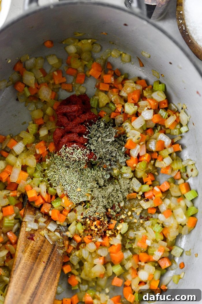 Adding tomato paste, dried basil, rosemary, sage, and red pepper flakes to sautéed vegetables