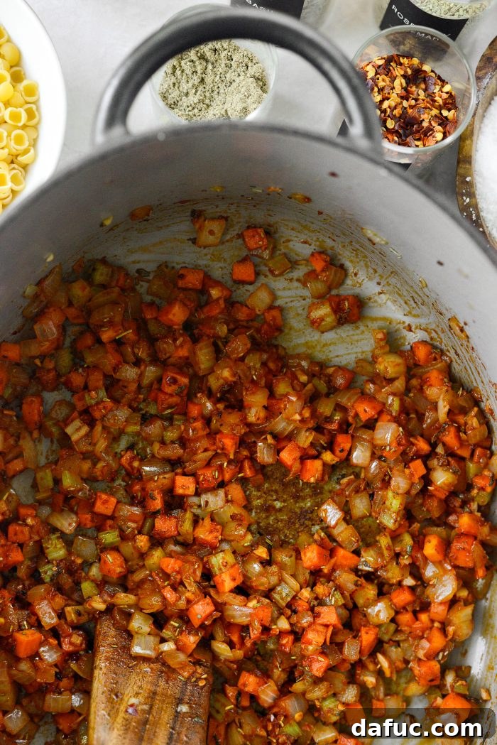 Stirring the tomato paste and herbs into the vegetables, cooking for a few minutes